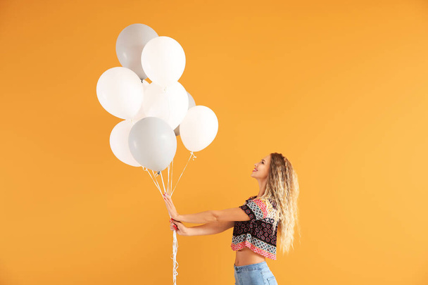 Schöne junge Frau mit Luftballons auf farbigem Hintergrund - Foto, Bild