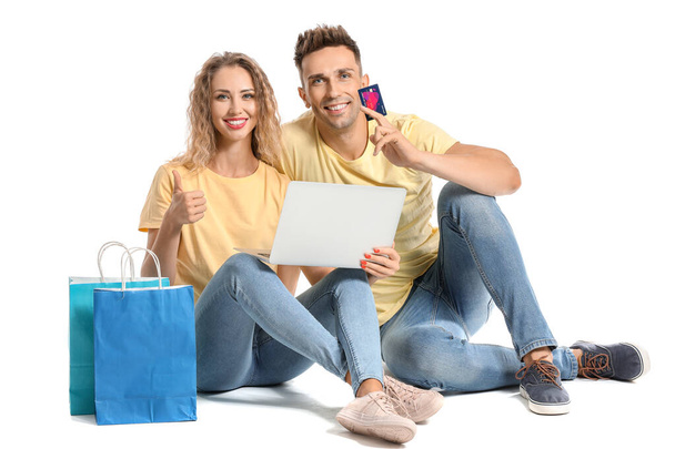 Young woman with credit card, shopping bags and laptop on white background - Photo, Image
