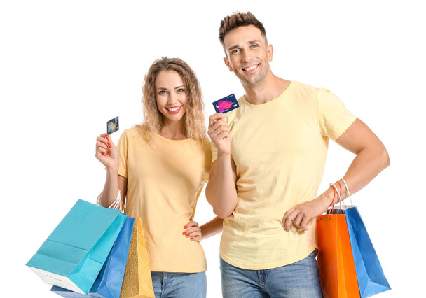 Beyaz arka planda kredi kartları ve alışveriş torbaları olan genç bir çift. - Fotoğraf, Görsel