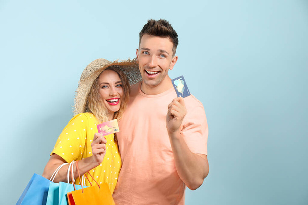 Young couple with credit cards and shopping bags on color background - Photo, Image