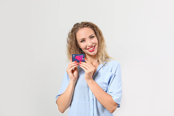 Молода жінка з кредитною карткою на світлому фоні
 - Фото, зображення