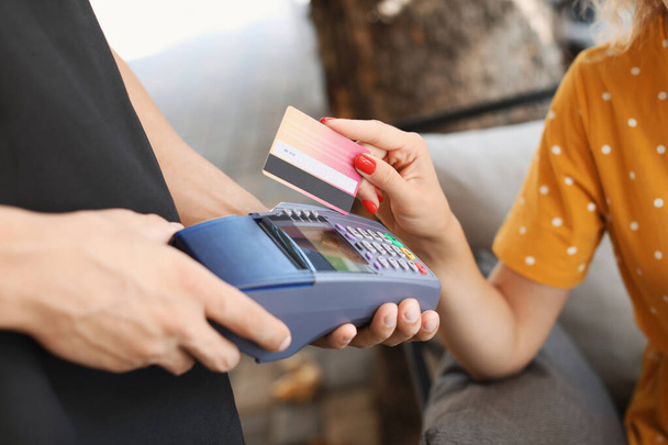 Young woman paying by credit card in cafe, closeup - Foto, afbeelding