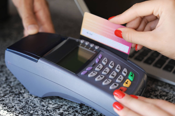 Jeune femme payant par carte de crédit dans un café, gros plan
 - Photo, image