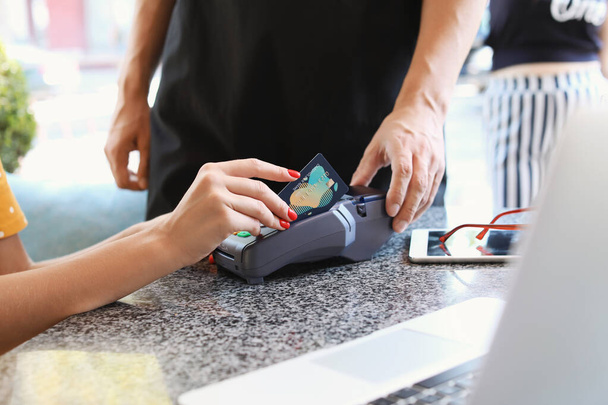 Mujer joven pagando con tarjeta de crédito en la cafetería
 - Foto, imagen