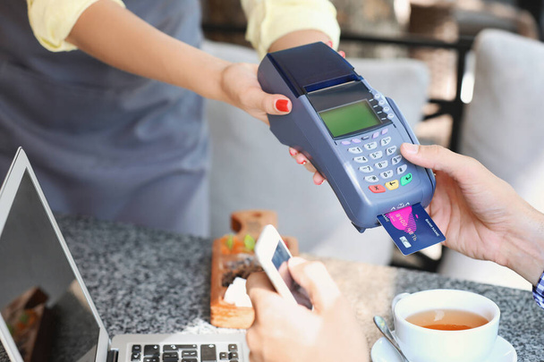 Fiatal férfi hitelkártyával fizet a kávézóban, közelkép - Fotó, kép