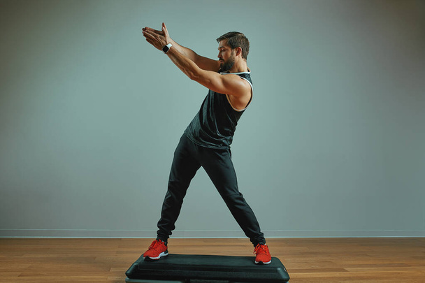 м'язистий молодий чоловік тренується на платформах на сірому фоні в студії
 - Фото, зображення