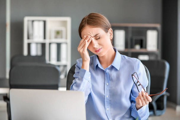 Fiatal nő szenved fejfájás az irodában - Fotó, kép