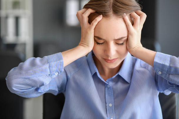 Νεαρή γυναίκα που υποφέρει από πονοκέφαλο στο γραφείο - Φωτογραφία, εικόνα