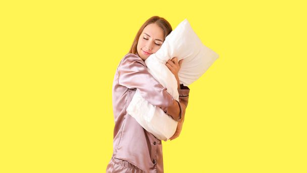 Bella giovane donna con cuscino su sfondo di colore
 - Foto, immagini