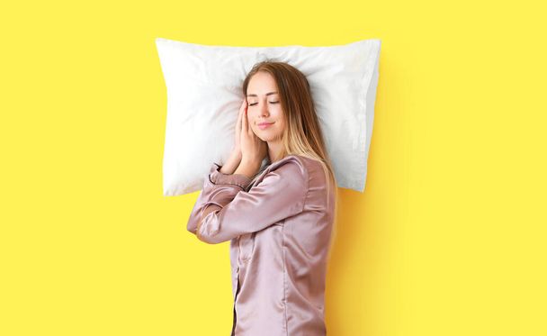 Sleeping young woman with pillow on color background - Foto, Imagen
