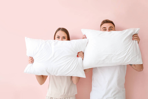 Νεαρό ζευγάρι με μαξιλάρια στο φόντο χρώμα - Φωτογραφία, εικόνα