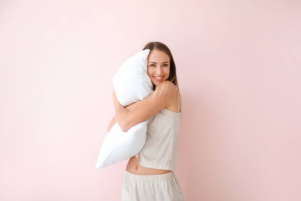 Young woman with pillow on color background - Фото, изображение