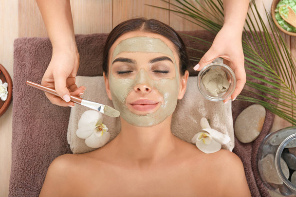 Cosmetologist aplicando máscara no rosto da jovem mulher no salão de spa
 - Foto, Imagem