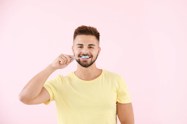 Portrait of man brushing teeth on color background - Photo, image