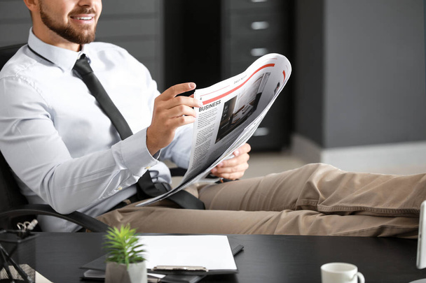 Handsome businessman reading newspaper in office - Zdjęcie, obraz
