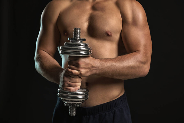 Handsome male bodybuilder with dumbbell on dark background - Φωτογραφία, εικόνα
