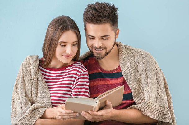 Portrait of happy young couple reading book on color background - Foto, Imagem