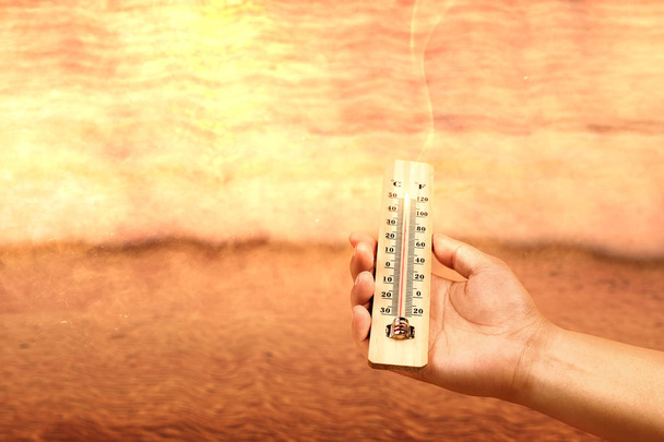 Hand holding thermometer with high temperature on the beach with - Foto, imagen