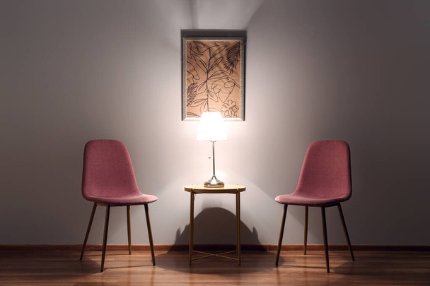 Cadeiras com mesa e lâmpada brilhante à noite
 - Foto, Imagem