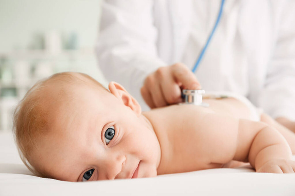 Pediatrician examining cute baby in clinic, closeup - Photo, Image