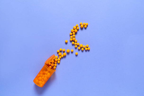 Sklenice a rozptýlené vitamíny ve tvaru písmene C na barevném pozadí - Fotografie, Obrázek