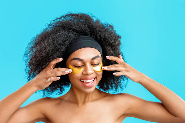 Portrait of beautiful African-American woman with under-eye patches on color background - Fotoğraf, Görsel