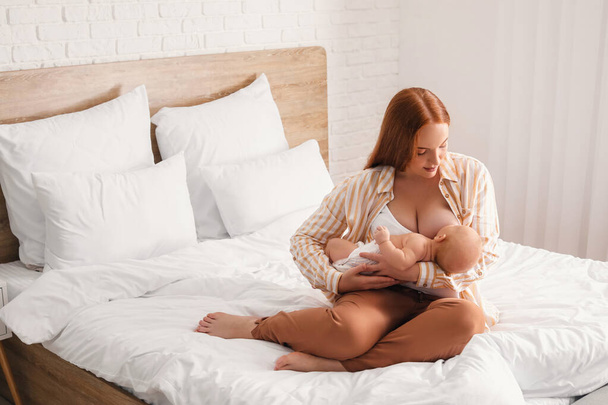 Jonge vrouw borstvoeding haar baby thuis - Foto, afbeelding