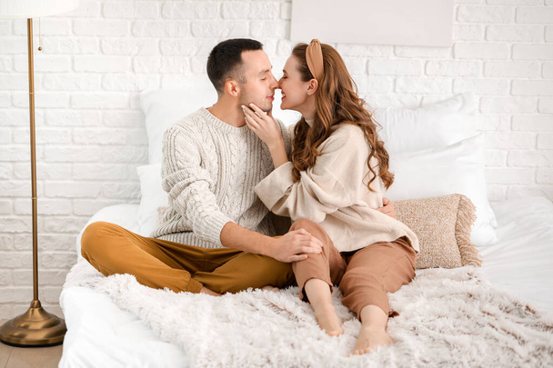Beautiful young couple sitting on bed at home - Photo, Image