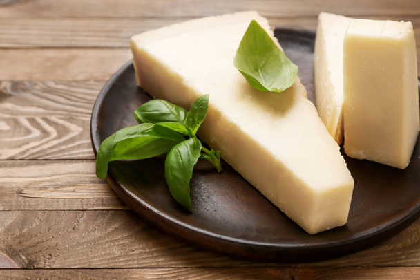 Assiette avec fromage parmesan savoureux sur fond en bois
 - Photo, image