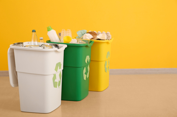 Контейнеры с различными видами мусора возле цветной стены. Концепция переработки отходов
 - Фото, изображение
