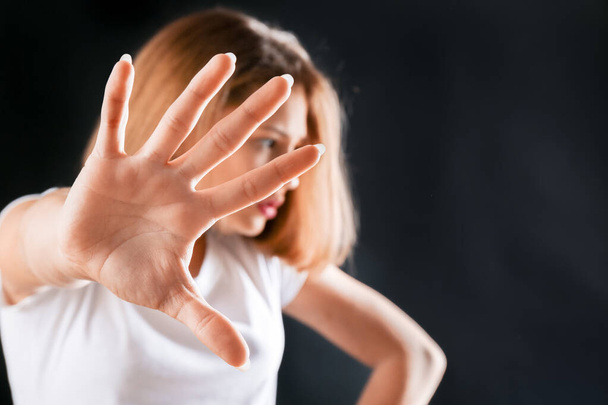 Cute teenage girl showing stop gesture on dark background - Фото, изображение