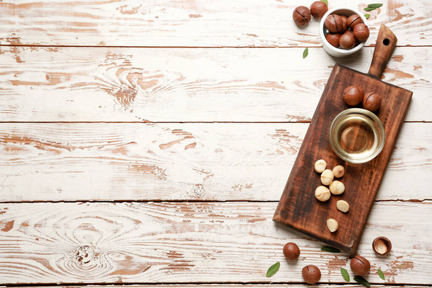 Lekkere macadamia noten met olie op houten ondergrond - Foto, afbeelding