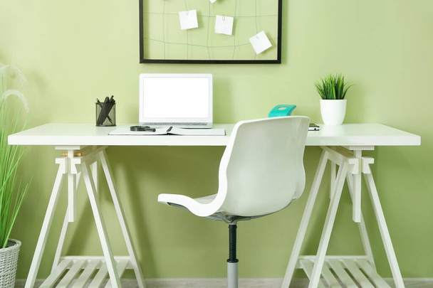 Moderno lugar de trabajo elegante con ordenador portátil cerca de la pared de color
 - Foto, Imagen