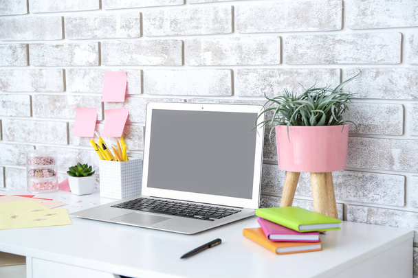 Modern stylish workplace with laptop near brick wall - Photo, Image