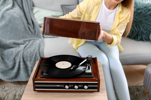 Krásná mladá žena poslouchá hudbu přes gramofon doma - Fotografie, Obrázek