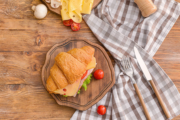 Board with tasty croissant sandwich on wooden table - Foto, Imagen