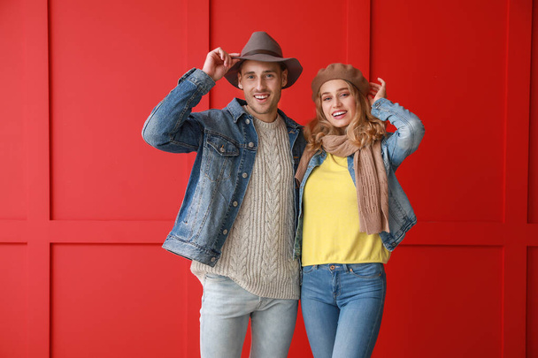 Feliz pareja joven en ropa de otoño caliente sobre fondo de color
 - Foto, Imagen