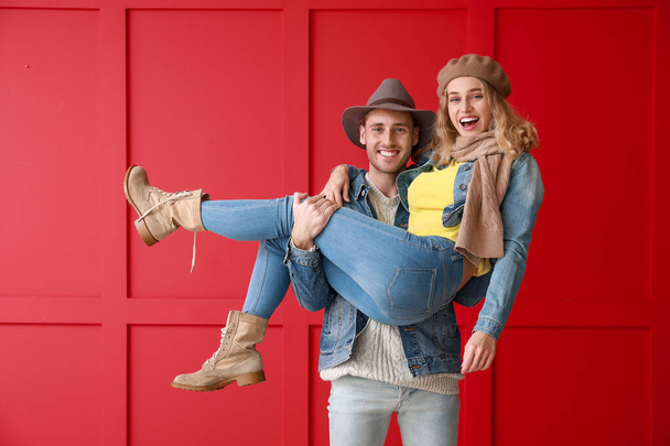 Happy young couple in warm autumn clothes on color background - Photo, Image