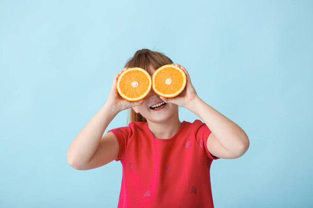 Cute little girl with orange on color background - Foto, afbeelding