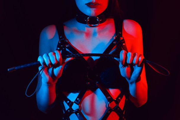 girl in a leather harness holds a Flogger whip in her hands - Foto, Imagem