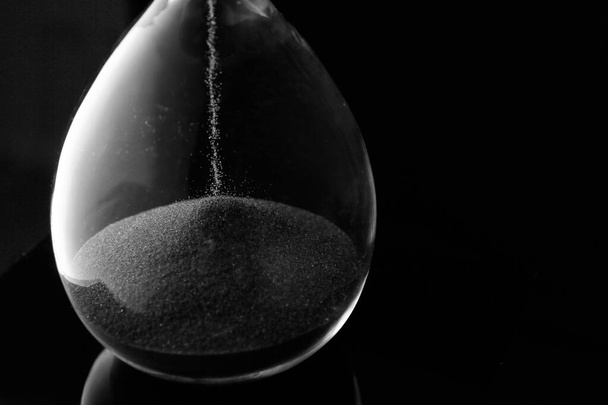 Reloj de arena de cristal sobre fondo oscuro, primer plano
 - Foto, Imagen