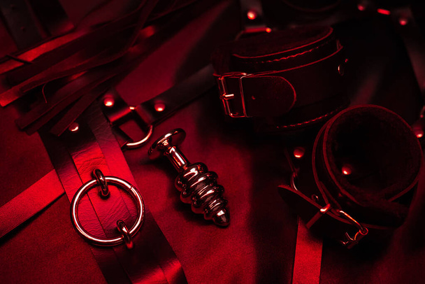 металлическая анальная пробка и кожаные наручники с удушителем. БДСМ-игрушки - Фото, изображение