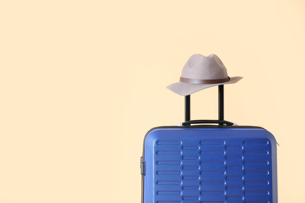 Maleta y sombrero embalados sobre fondo de color. Concepto de viaje
 - Foto, imagen