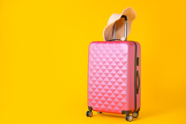 Packed suitcase and hat on color background. Travel concept - Valokuva, kuva