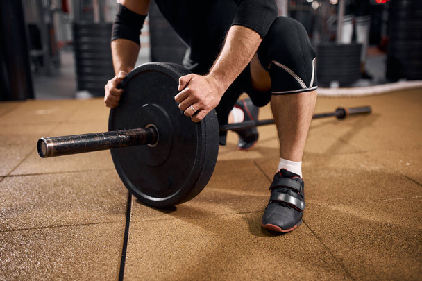 Powerlifter changing iron discs in gym - Zdjęcie, obraz