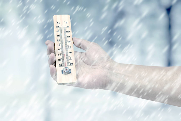 Hand holding wooden thermometer with the low temperature at wint - Foto, immagini