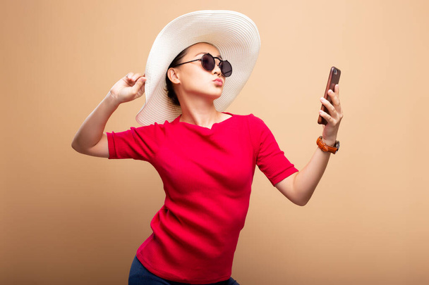 Femme portant chapeau et lunettes de soleil utilisent un téléphone intelligent isolé sur bac
 - Photo, image