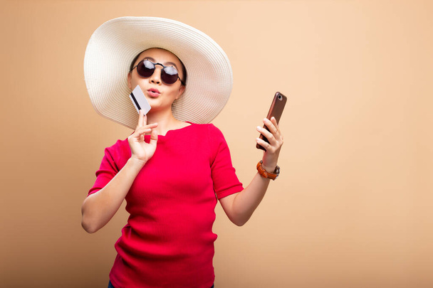 Mulher usando chapéu e óculos de sol usar telefone inteligente e cartão de crédito
 - Foto, Imagem