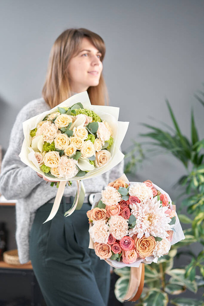zwei schöne Sträuße gemischter Blumen in Frauenhänden. die Arbeit des Blumenhändlers in einem Blumenladen. frische Schnittblume. - Foto, Bild