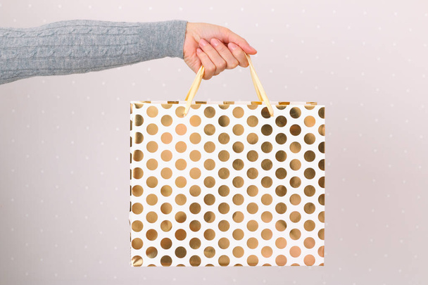 Close-up of a woman holding a paper gift bag in her hand. The concept of shopping and sales - Photo, image